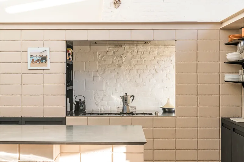Kitchen nook with horizontal tile cladding, painted brick backsplash and open shelving under strip lighting