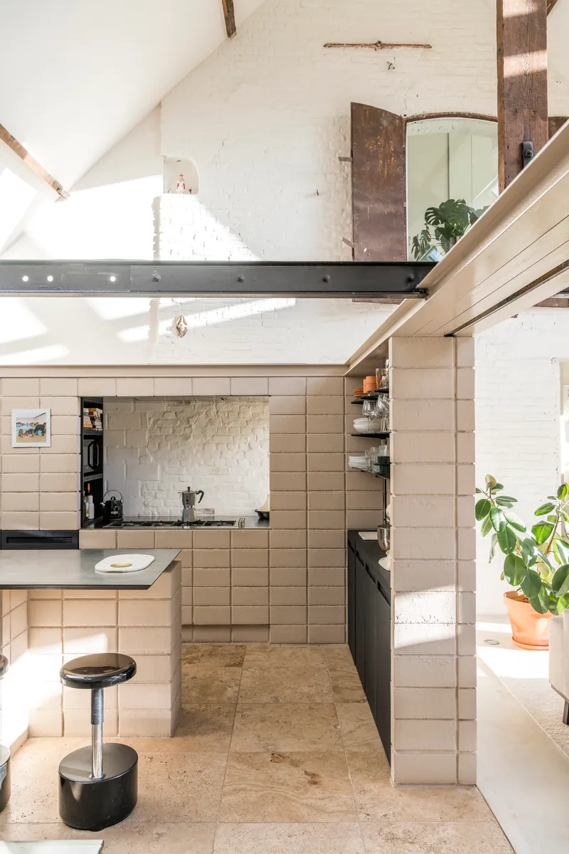 Kitchen with cream tile cabinetry and exposed whitewashed brick alcove under skylights