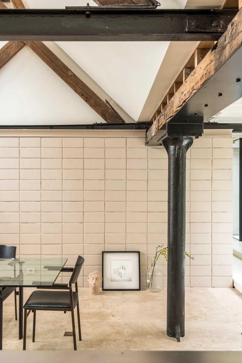 Cast iron column supporting steel beams beside a cream tiled wall in daylight