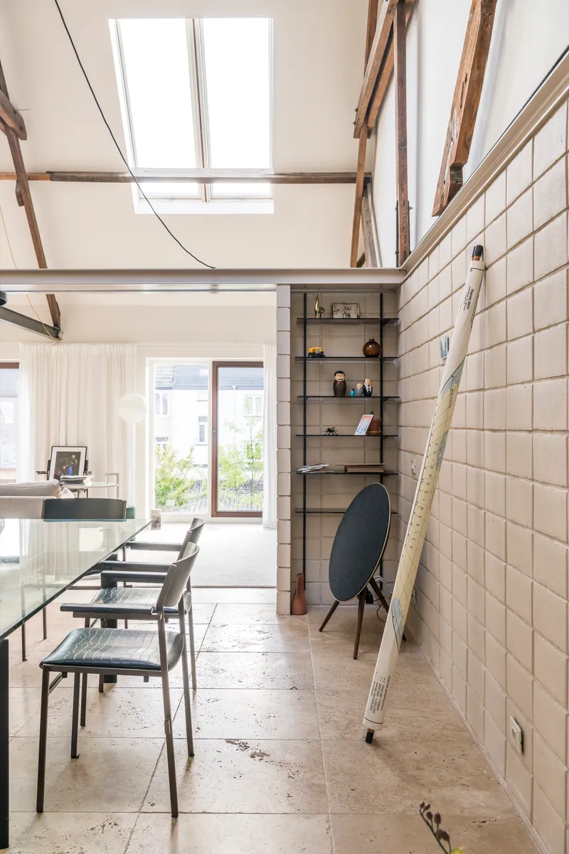Dining space with tiled walls and ladder propped against the surface under roof skylights