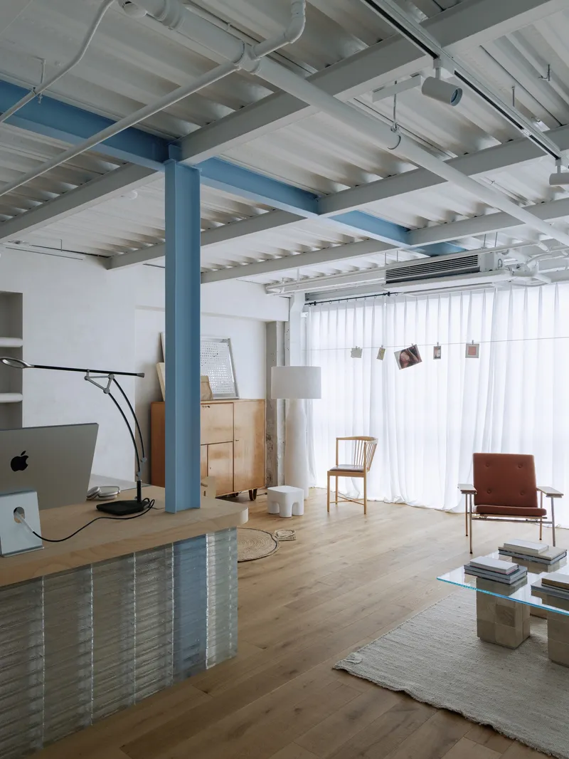 Living area with blue steel column and white ribbed ceiling structure above timber flooring