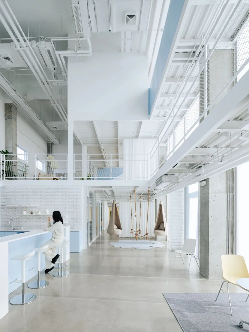 Ground floor lounge with white tile walls, rope swings and a person seated at a high counter