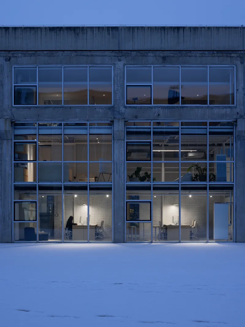 Illuminated office facade with steel frame and horizontal banding at blue hour in winter