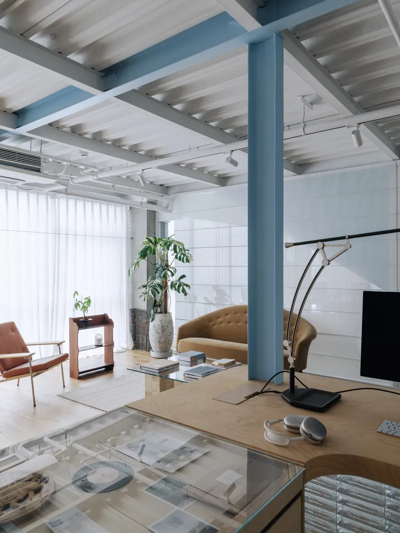 Interior view showing blue column framing a seating area with potted plants near white tiled wall