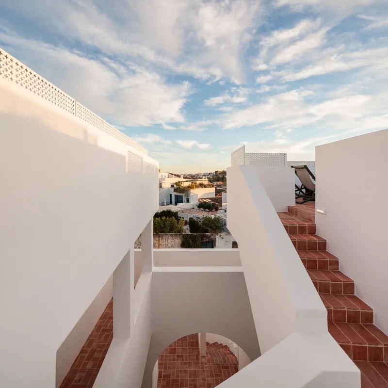 Rooftop terraces with terracotta stairs and white walls under a wispy afternoon sky