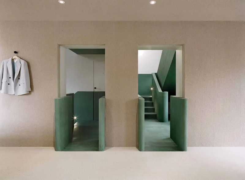 Two recessed stair openings with green painted walls beneath a beige ceiling with recessed lights