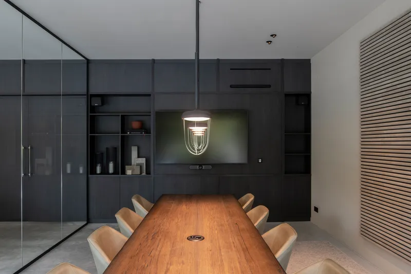 Dining room with dark millwork wall, recessed shelving, and pendant light above timber table