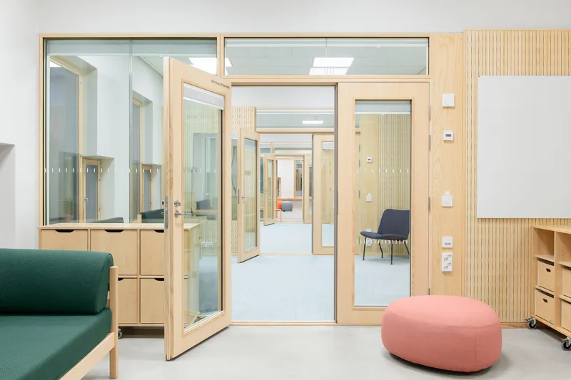 Interior corridor with timber-framed glass doors opening between rooms with light wood joinery