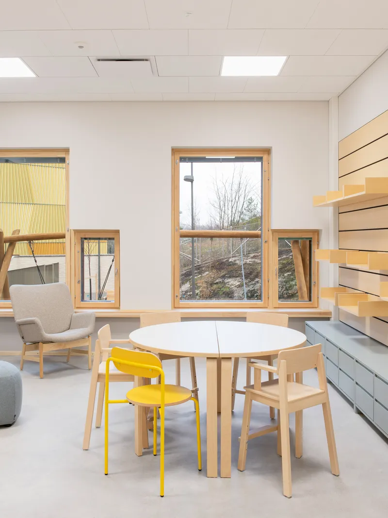 Interior room with timber-framed windows overlooking bare winter trees and a round white table