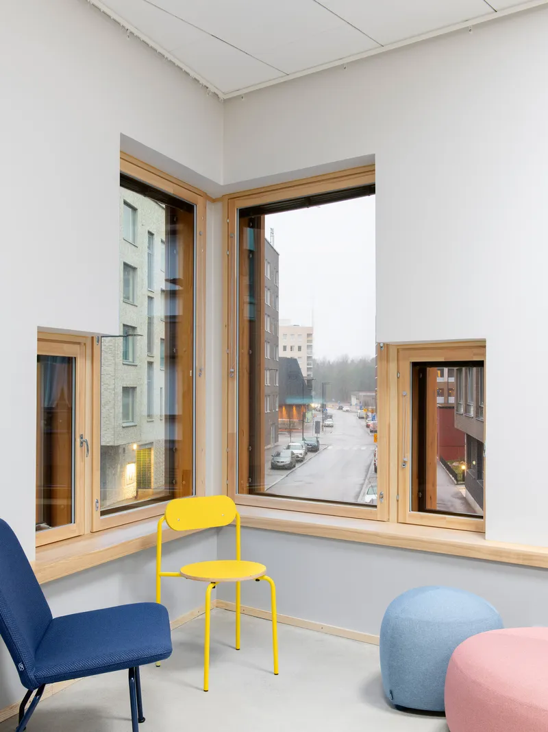 Corner window seat with timber frames looking onto a winter street with parked cars
