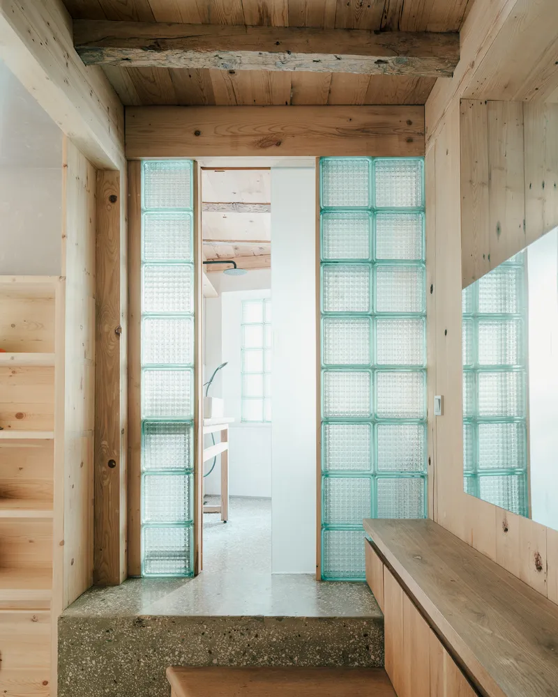 Entryway framed by glass block walls and timber structure with view into interior