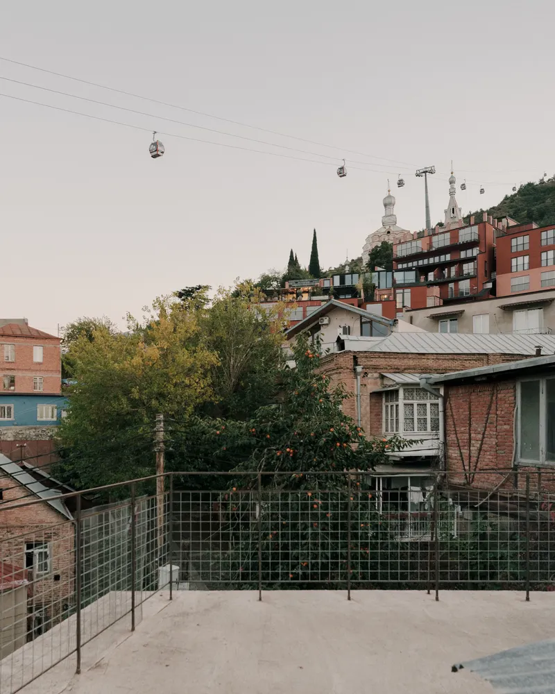 Rooftop terrace with glass railing looking toward hillside neighborhood and cable car lines