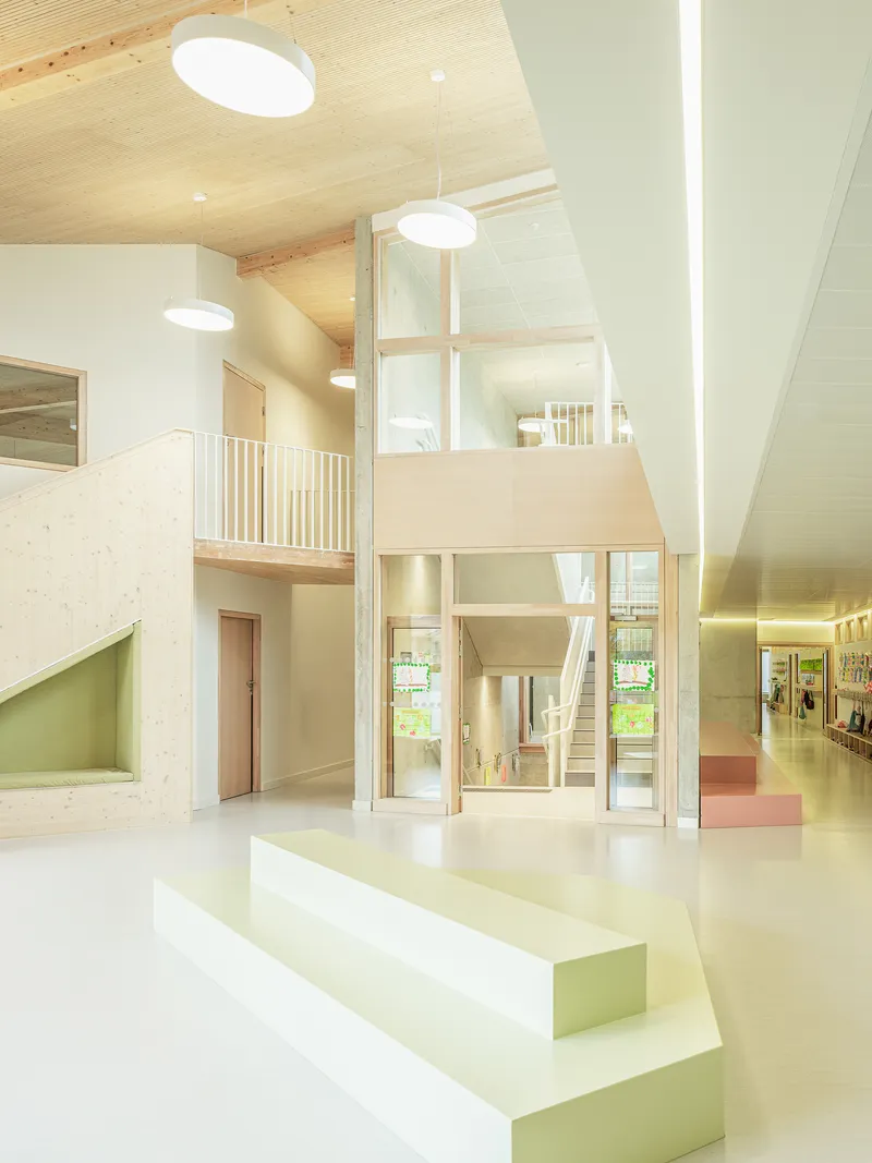 Double-height interior space with pale green stepped platforms and exposed timber ceiling structure