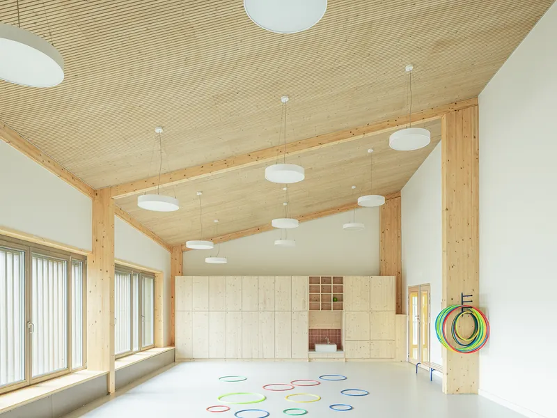 Interior room with ribbed timber ceiling, exposed beams, white pendant lights and colorful hoops on the floor