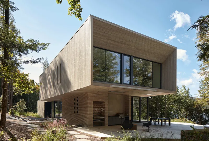 Cantilevered upper level with vertical wood cladding above covered terrace with brick accent wall