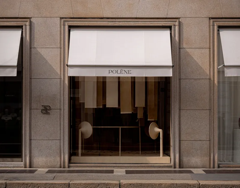 Street level view of bronze-framed storefront with white awning and glass doors beneath ashlar stone facade