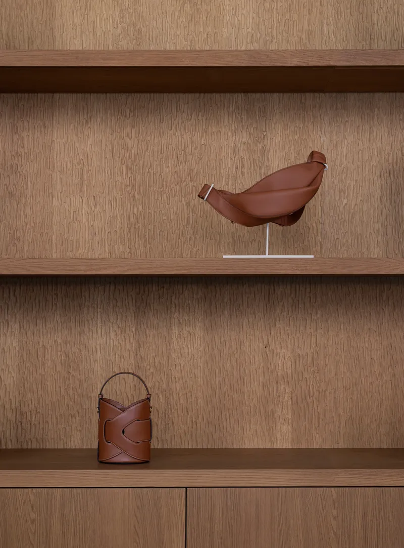 Built-in shelving with oak veneer displaying a sculptural bird form and leather vessels