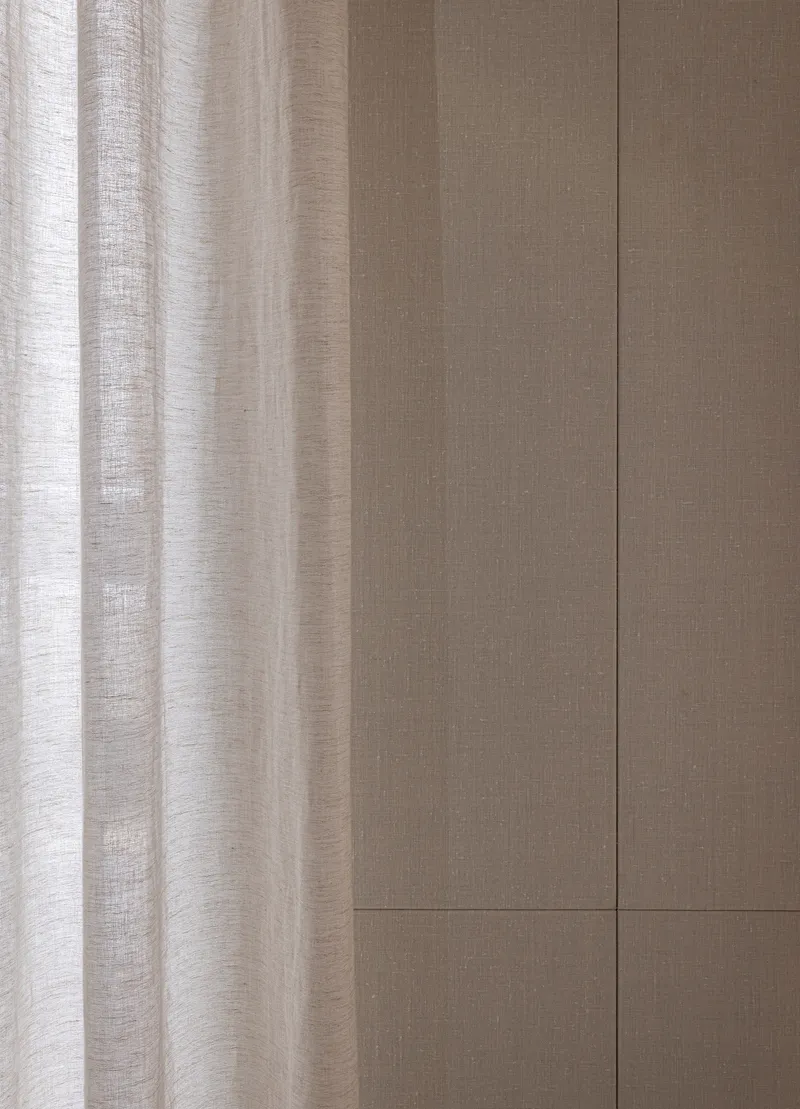 Linen curtain beside grooved oak wall panels with horizontal joint detail in natural light