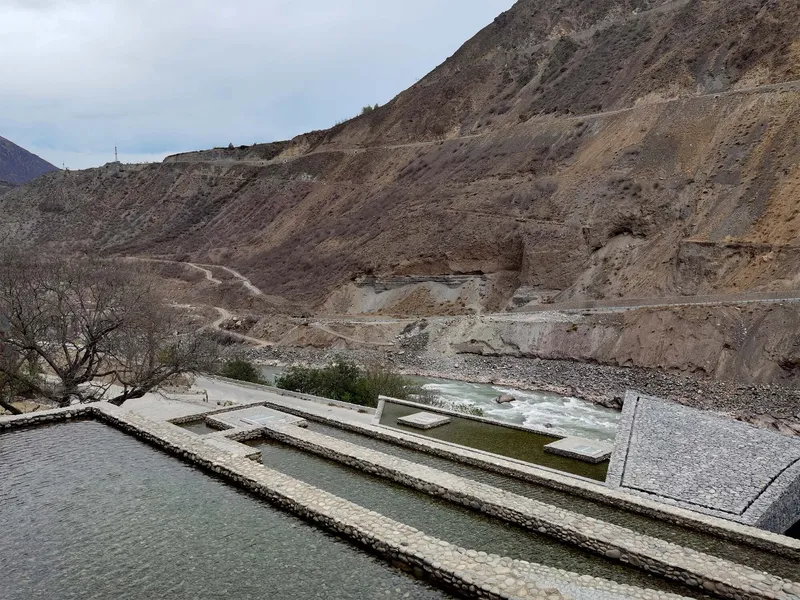 Water channels carved into stone terraces overlooking a riverbed in the barren mountain landscape