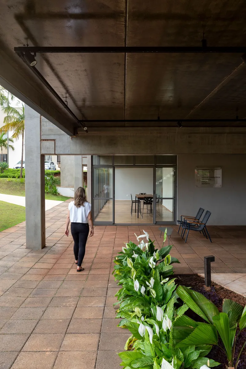 Covered terrace with terracotta pavers and planted bed as a woman walks toward the glazed interior