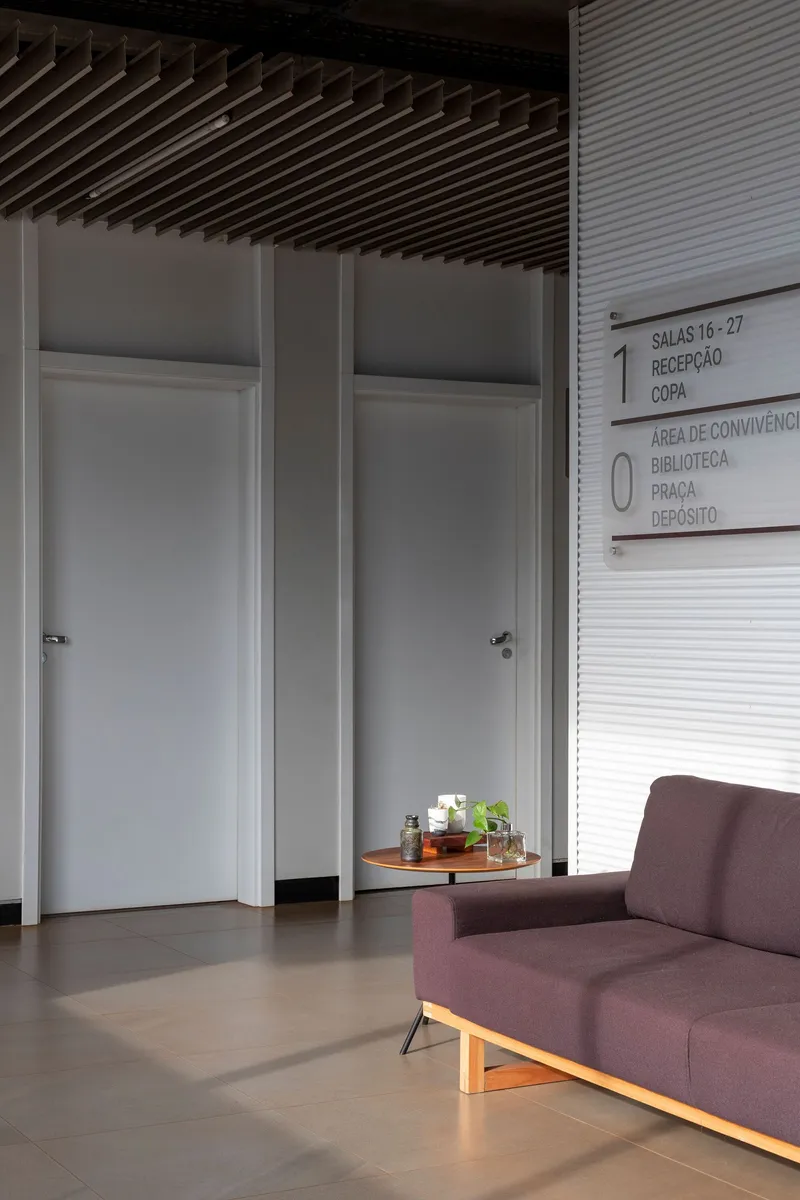 Interior corner with flush white doors beneath a wood slat ceiling and wayfinding signage