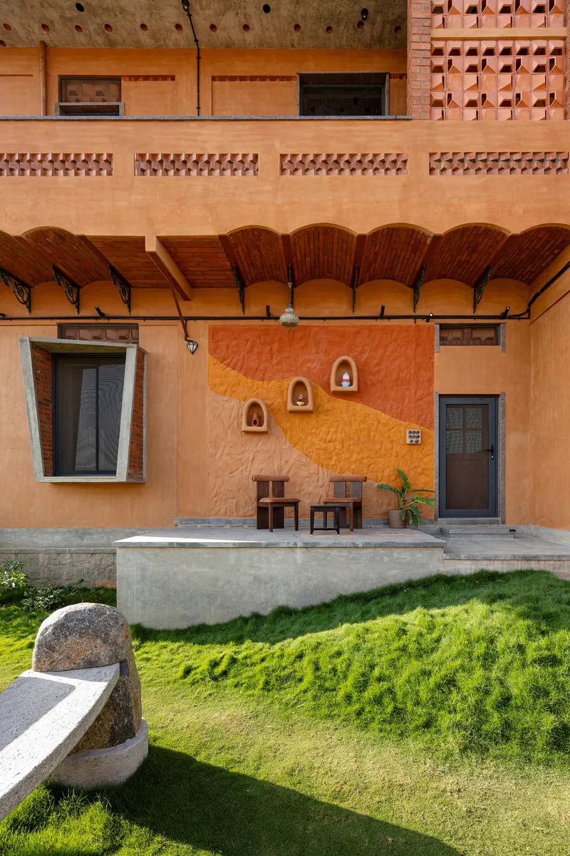 Covered terrace with exposed brick vaulted ceiling, niche wall ornaments, and lawn below