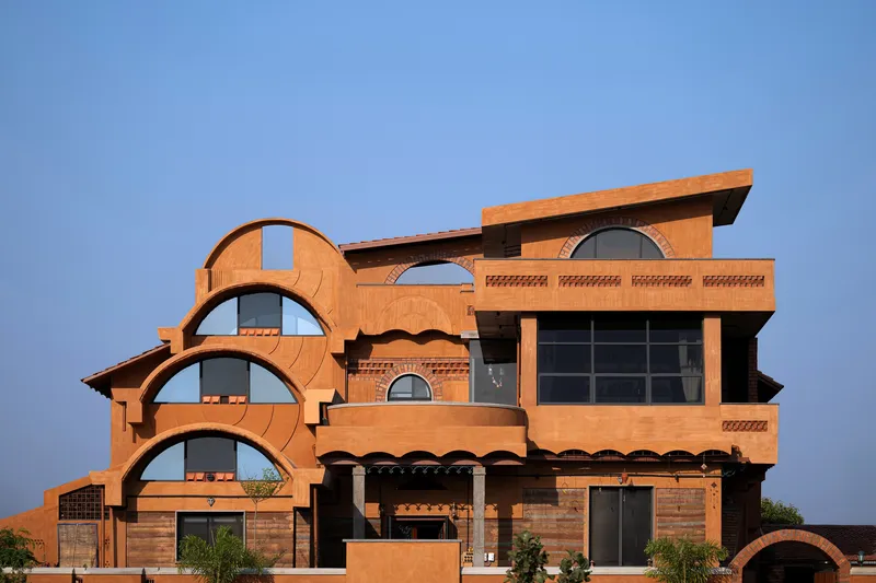 Facade with stacked circular arched windows and cantilevered flat roof plane in afternoon light