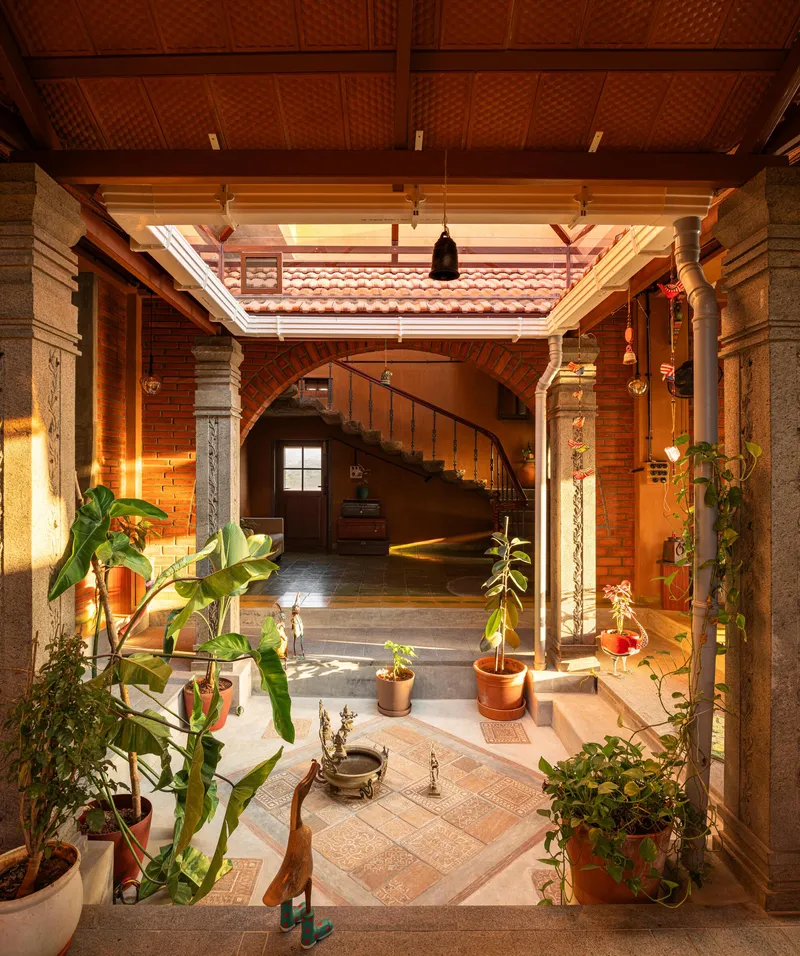 Interior courtyard with potted plants, carved stone columns, curved staircase and woven bamboo ceiling