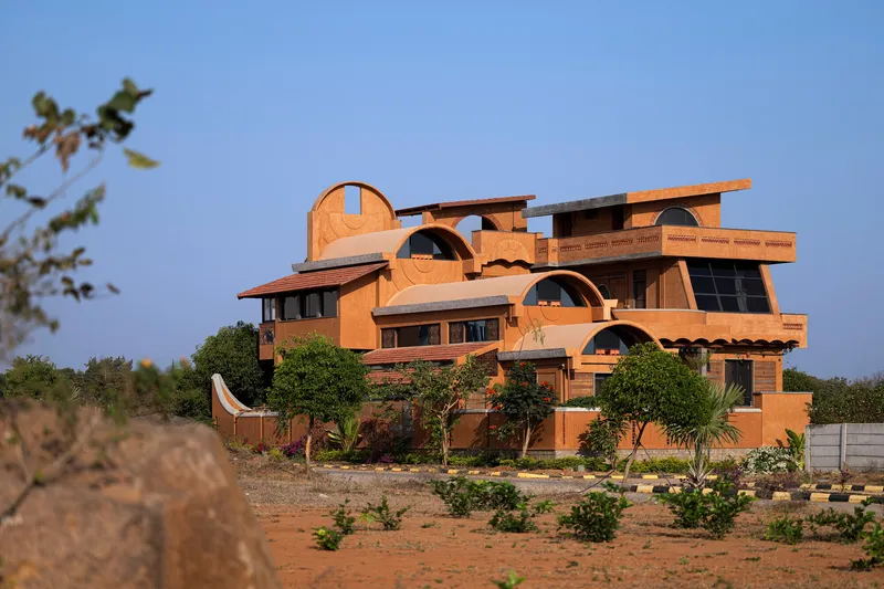 Full building view from a planted field showing the stacked arched forms at dusk