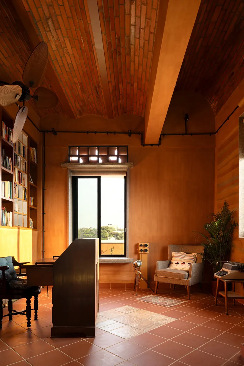 Library room with brick barrel vault ceiling and tall window overlooking landscape at golden hour