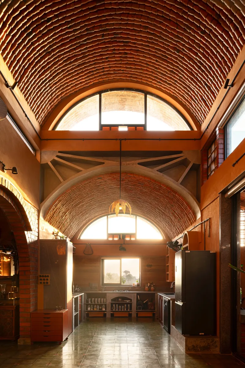 Interior corridor with exposed red brick barrel vault ceiling and clerestory windows letting in afternoon light