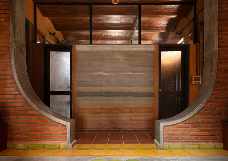 Entrance with curved concrete frame and layered timber door flanked by frosted glass panels