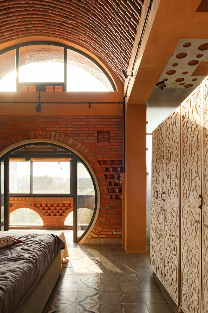 Bedroom with circular brick archway opening to adjacent space and decorative carved wooden closet doors