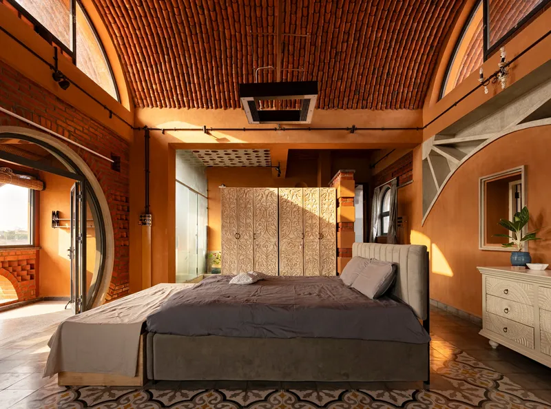 Bedroom with brick barrel vault ceiling and ornate wooden screen panels behind upholstered bed