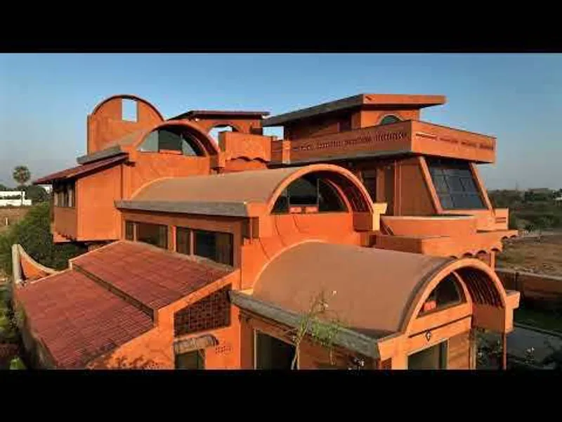 Aerial view of the terracotta-colored residence with barrel vault roofs and staggered terraces under a clear blue sky