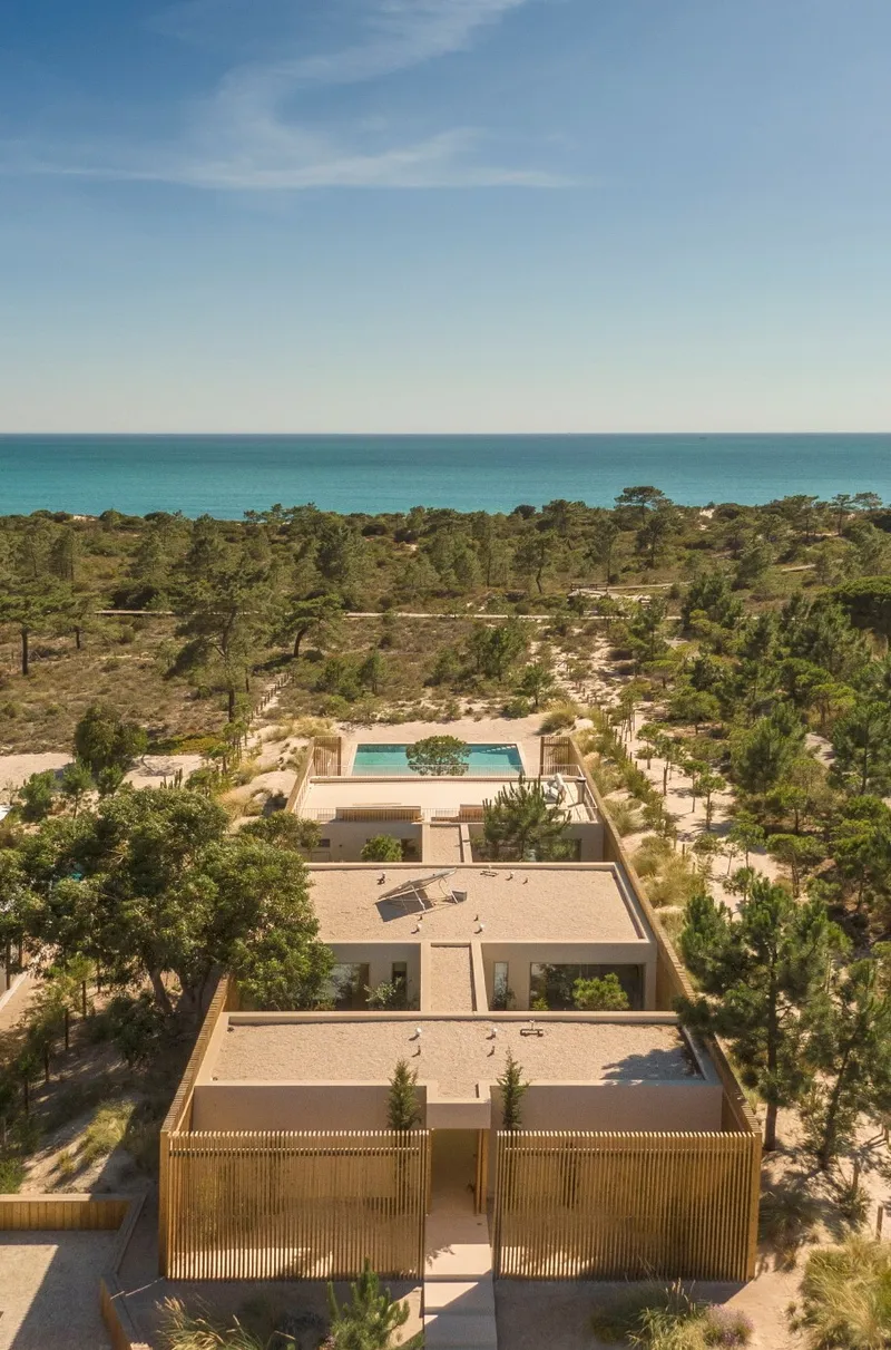 Aerial view of the residence with pool and flat roofs set among coastal pines