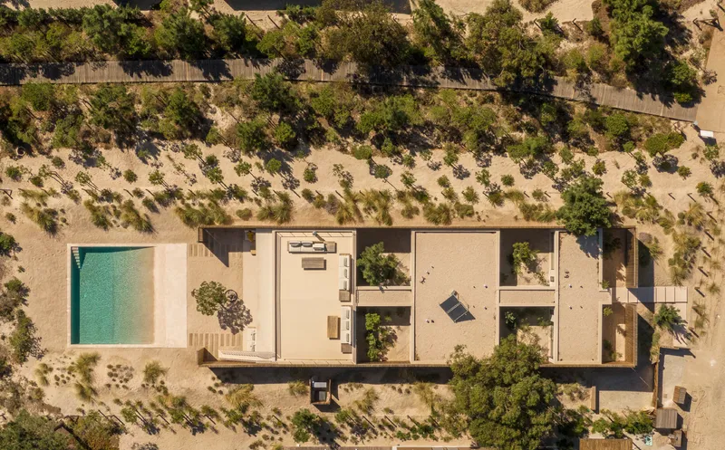 Aerial view of the linear residence with central courtyard pool surrounded by sandy terrain and scattered pines