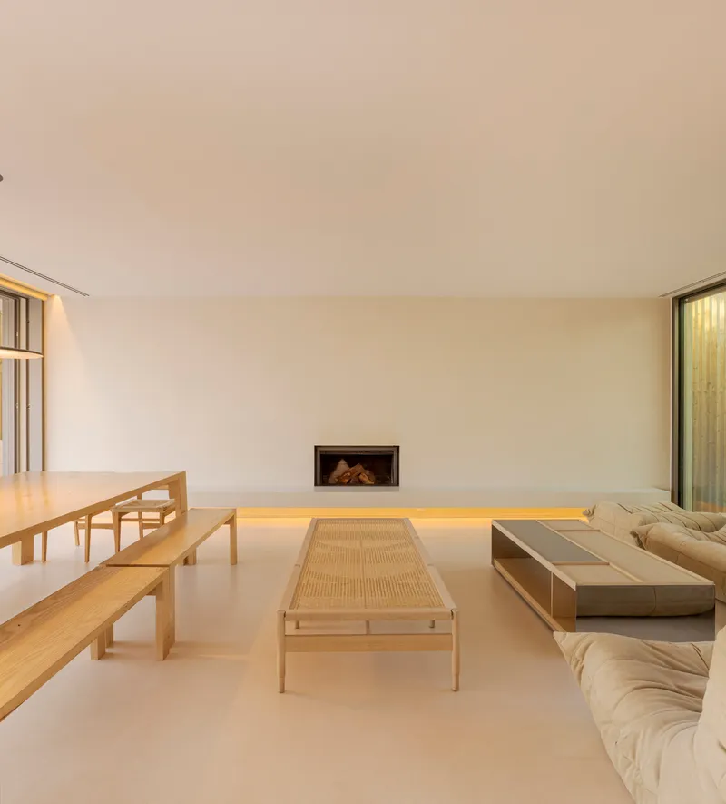 Living room with recessed fireplace, backlit floating bench and pale timber furniture under soft daylight
