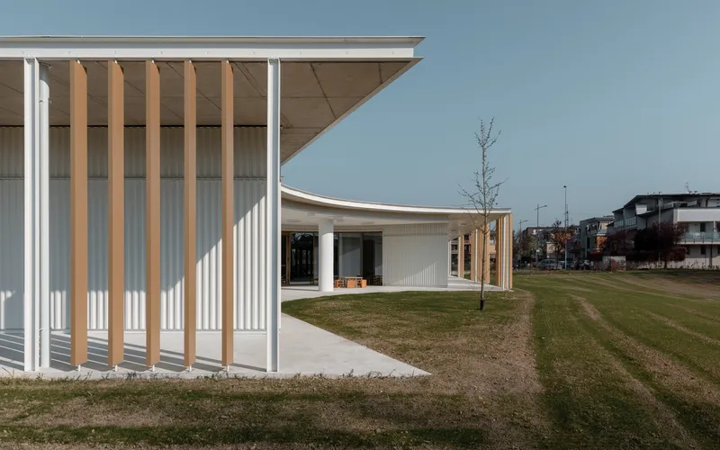 Corner detail of white corrugated cladding with vertical timber slats beneath a projecting roof overhang