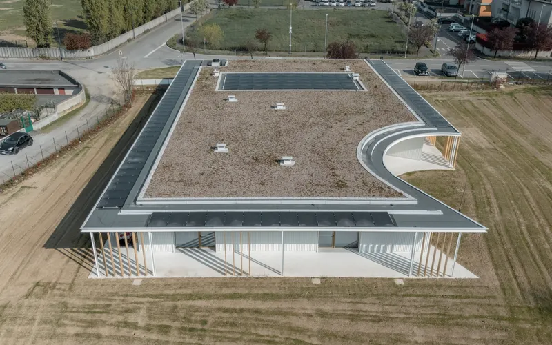 Drone view showing the rectangular gravel roof with curved corner volume and surrounding open landscape