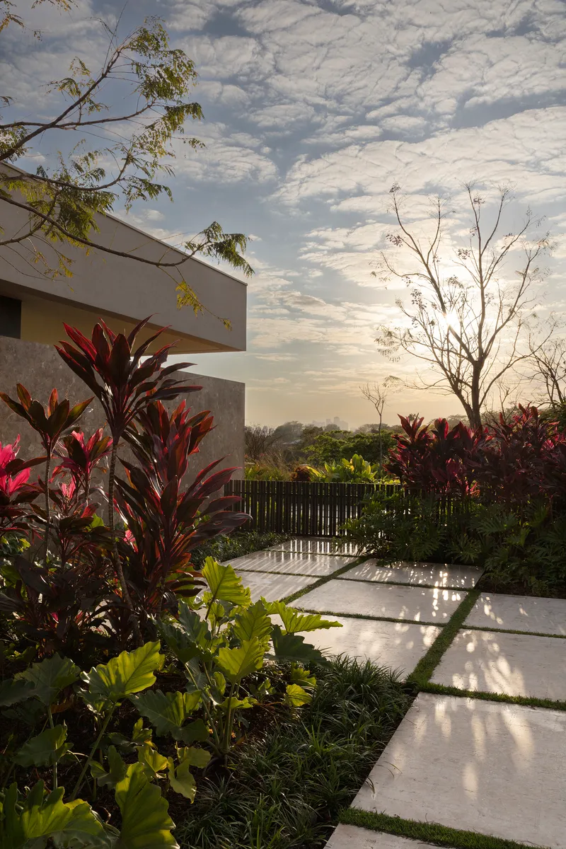 Planted terrace with red foliage and concrete pavers under a dramatic cloudy sunset sky