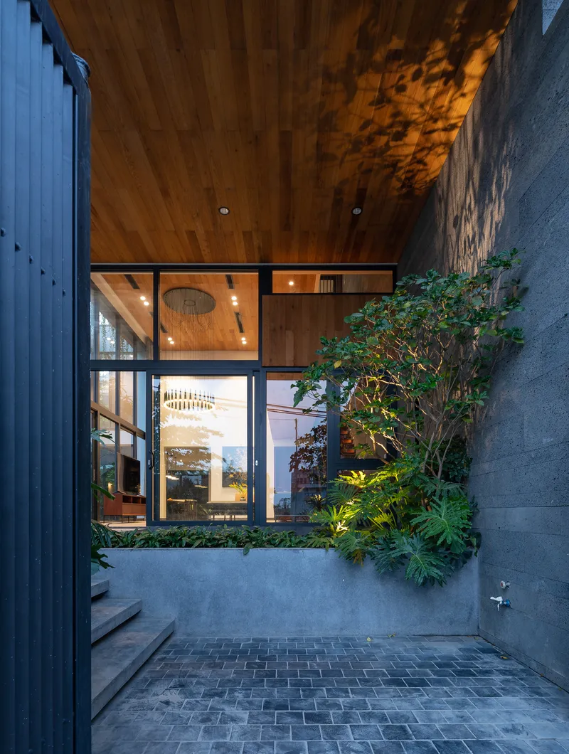 Interior courtyard at dusk with timber ceiling, planted beds and slate paving under soft illumination
