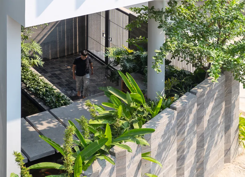 Elevated walkway with steel railings connecting planted terraces as a figure descends