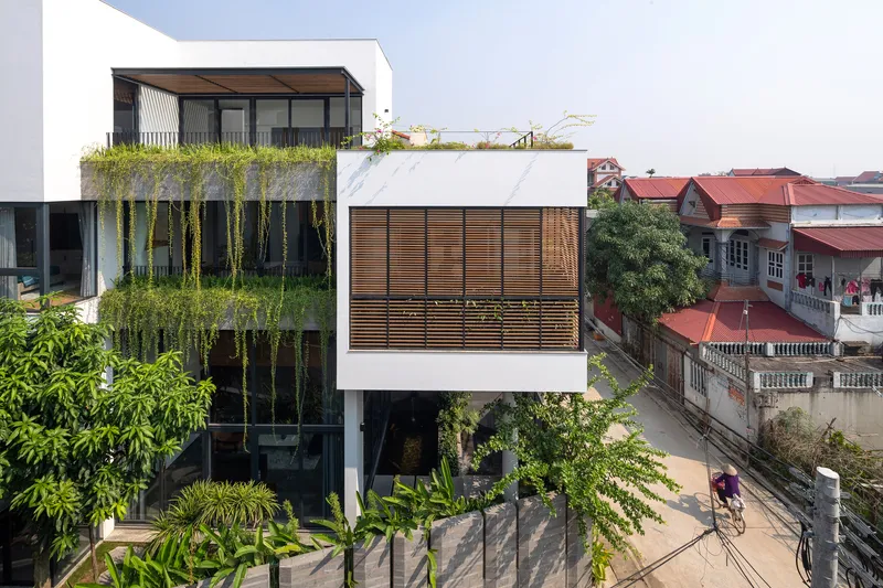 Street elevation showing stacked volumes with timber screens, cascading planters, and cyclists passing below