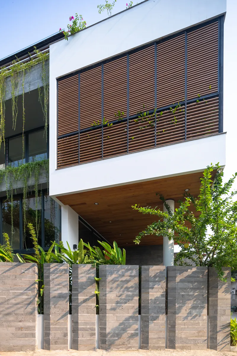 Street facade with horizontal timber slat screen above a cantilevered porch and stone-clad gate