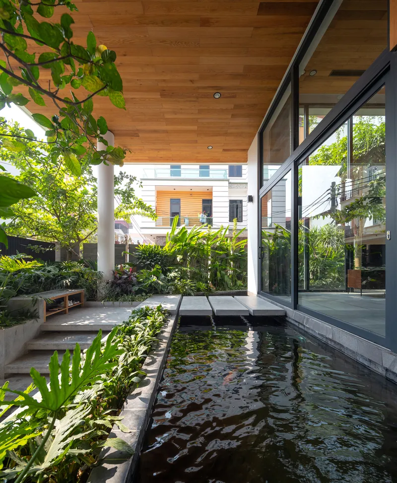 Covered courtyard with koi pond and glass walls looking into planted garden in daylight