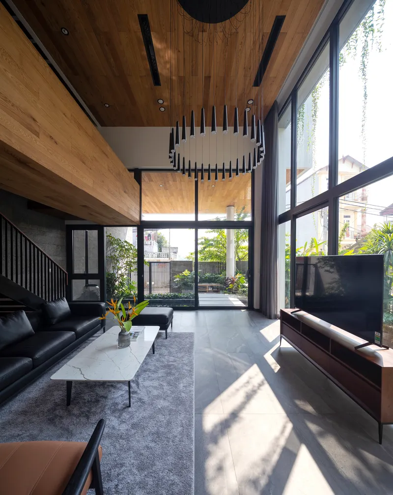 Double-height living room with timber ceiling and circular pendant light under afternoon sun