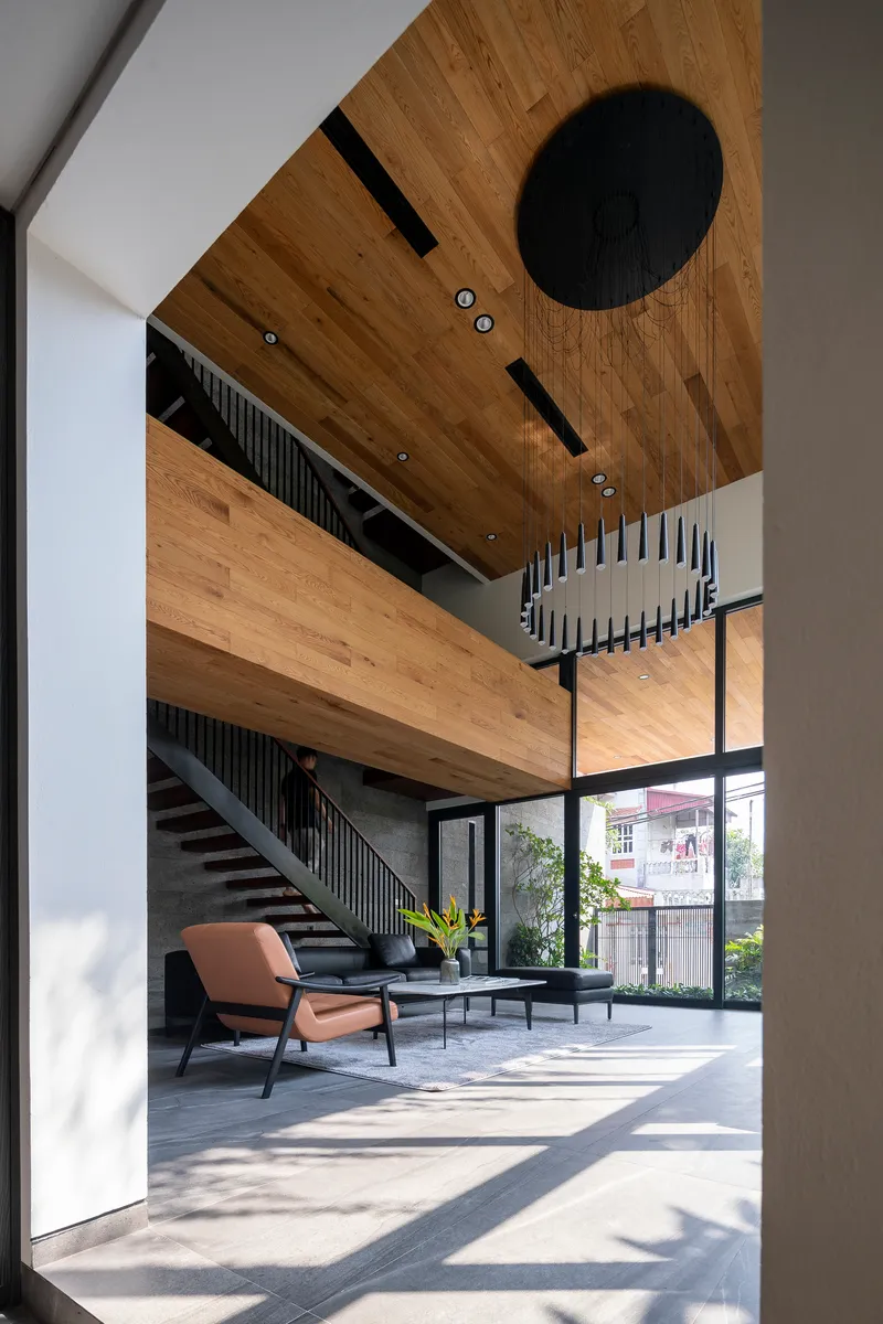 View through doorway into double-height space with floating timber bridge and metal staircase