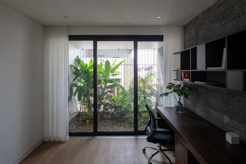 Home office with glazed doors opening to an interior garden courtyard with palms and grasses