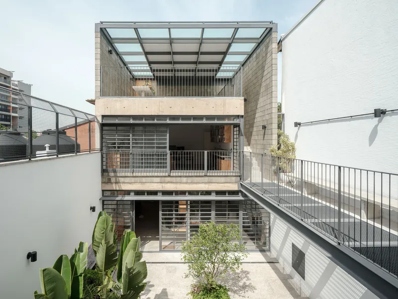 Interior courtyard with three-story concrete facade, metal walkways, glass block railings, and planted banana palms